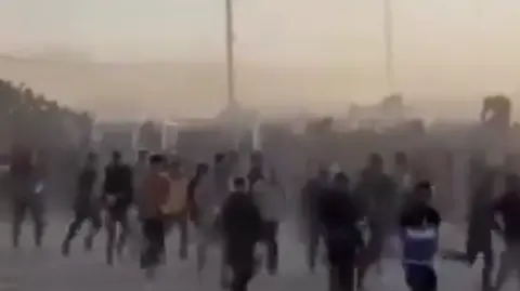 A screengrab from footage shows a crowd of Palestinians rushing towards an aid site