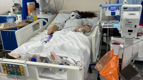 Gemma Hunter Gemma laid down in a hospital bed with monitoring a machines around her. Her neck is also in a brace.