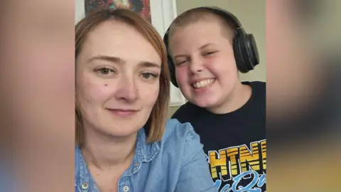 Claire Miller with her son Danny. Claire has shoulder-length brown hair, wearing a blue denim shirt. Danny has short brown hair, wearing a black t-shirt and headphones.