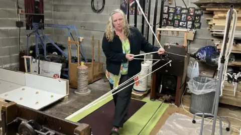BBC/Emily Johnson Caroline Rodgers operates a rope walk - a machine which suspends two bits of yarn between two points