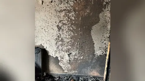 Nottinghamshire Fire and Rescue Service A photograph that shows the fire-damaged wall in the room at the property