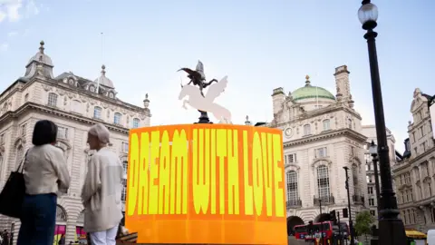 PA Media Two people in the foreground look at the new art installation 
