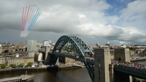 NNP The Red Arrows display team soar over the Tyne Bridge as thousands of runners cross it