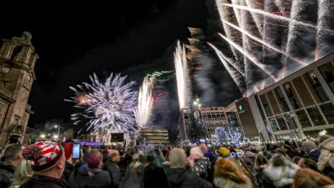 North News and Pictures Fireworks in Sunderland as crowds watch on. One man is wearing a woolly Sunderland football club hat.