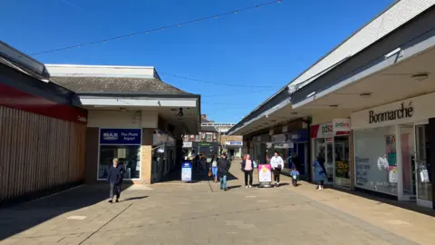 People walk through the Belvoir Shopping Centre in Coalville