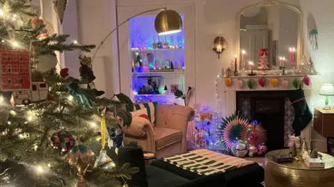 IWC Media Festive living room with a decorated Christmas tree, colourful ornaments, and a mantel adorned with candles and handcrafted paper garlands.