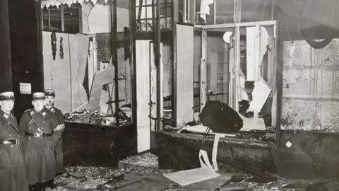 Yad Vashem Photo Archive A destroyed shopfront with Nazi officers standing by