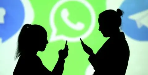 Reuters Two women are pictured silhouetted while using their mobile phones