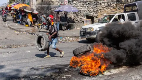 Getty Images A man sets a tire on fire during a demonstration in Port-au-Prince, Haiti