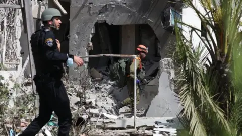 EPA Israeli security forces inspect a home in the city of Ashkelon that was hit by a rocket fired from the Gaza Strip (11 May 2021)