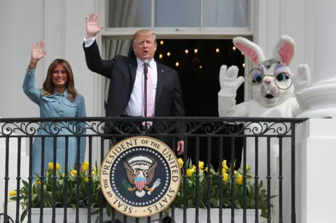 Jonathan Ernst/ REUTERS US President Donald Trump and first lady Melania Trump wave beside a person in an Easter Bunny costume on the Truman balcony of the White House