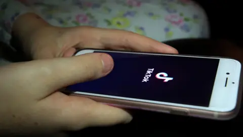 PA Media Someone using TikTok on their phone