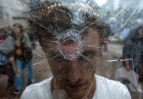  Seth Herald / Getty Images A protester holds a shattered window, mimicking a gun shot to his forehead, as students from across Nashville, US, walked out of schools to demand stricter gun laws in the state.