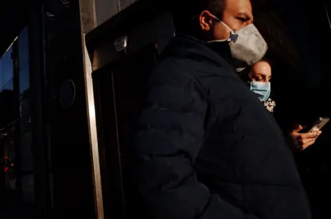 Getty Images A couple wearing masks walk along a near-deserted Oxford Street in London, England, before the new rules were announced