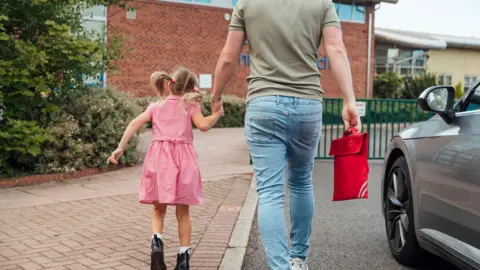 Getty Images Parent with child at school gates