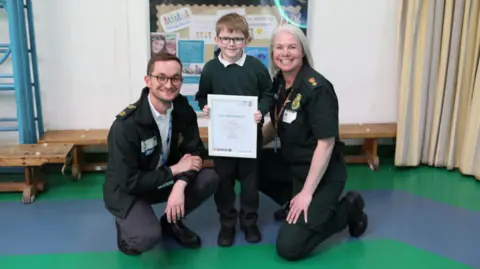 EEAST Dimitri Clark holds his certificate with Tom Abell and Michelle Behn either side of him