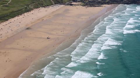 An aerial picture of Fistral beach showing people on the sand and in the sea