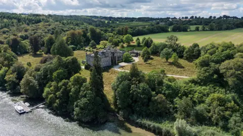 Reuters An aerial view of a castle, surrounded by trees and fields. It is overlooking a river. There is a boat on the river.