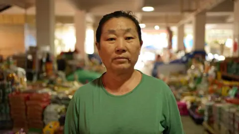 Xiqing Wang/BBC Li Mianzhen in a green t-shirt at the market where she runs a stall