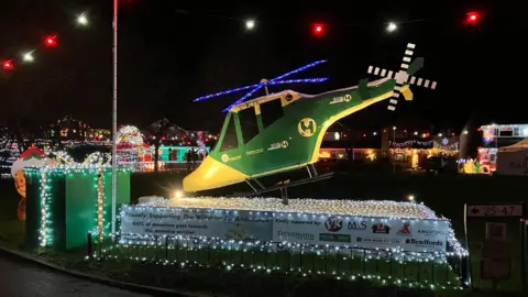 A helicopter made of lights complete with rotary blades and a giant parcel