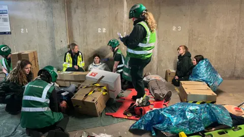 Medical personnel gather around "casualties' in an underground car park.