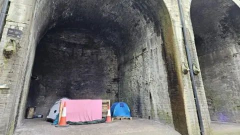 Aisha Iqbal/BBC A number of tents belonging to rough sleepers are shown pitched up underneath the arches of a viaduct.