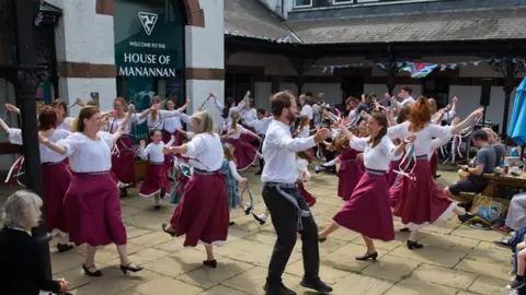 Celtic Gathering a group of people dancing in burgundy dresses and white tops