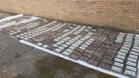 A car park with multiple packages on the ground containing cocaine