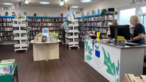 Librarian desk to right with shelves of books in the background and bunting hanging from the ceiling