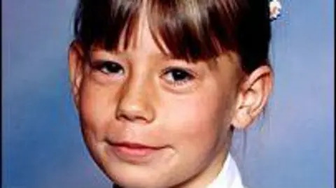 Lauren Pilkington-Smith, a 10-year-old girl, is photographed with brown hair and a fringe. Smiling, she is in front of a blue background of the type used by school photographers.