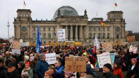 Reuters Dozens of protesters gathered outside Germany's parliament holding up signs. 