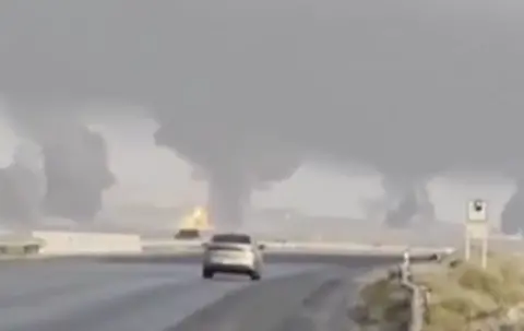 Telegram Image posted on social media shows a car driving along a road with smoke rising in the distance ahead of it