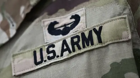 Military fatigues, with a badge attached that says "US Army" 