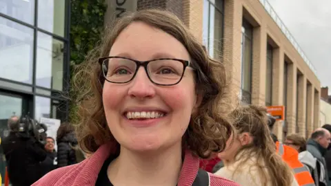 A smiling woman outside the library building