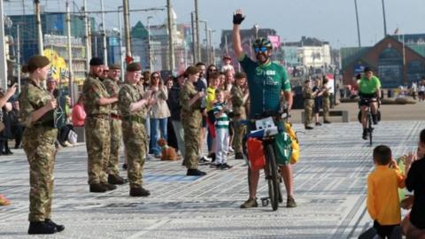 Jordan Wylie arrives at Blackpool Tower on his bike, watched on by army cadets and the public