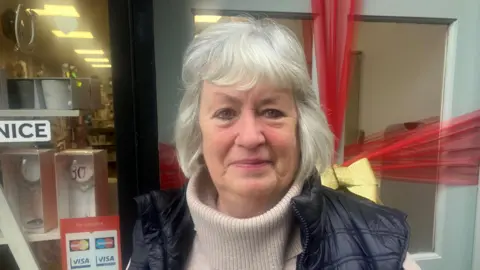 Photograph of Julie Kelly outside her balloon and card shop on Market Street in Ashton-under-Lyne