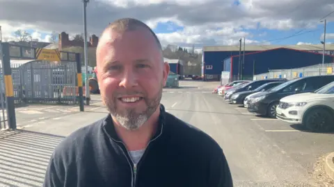 Photograph of Mike Robinson in front of a Tameside Council waste depot 