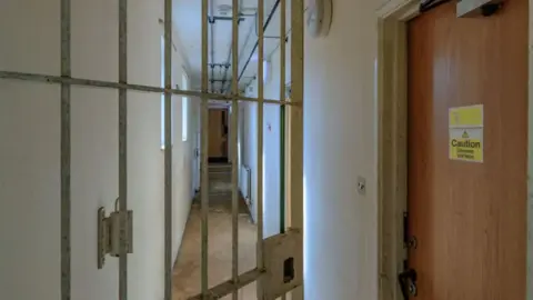 An open gate and a door with a sign saying "caution: uneven surface" at Campsfield House.