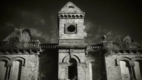 A black and white slightly eerie image of the brick front of the Rosefield Mills building