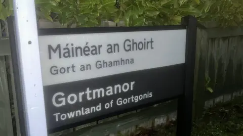 A street sign that says in Irish "Máinéar an Ghoirt - Gort an Ghamhna" Below it says in English "Gortmanor - Townland of Gortgonis"