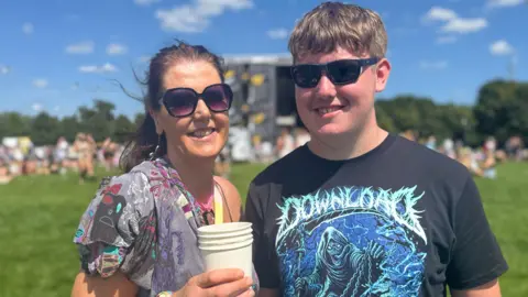 Lesley Lapsley, in a patterned top and sunglasses, with her son Aidan, wearing a Download t-shirt and shades