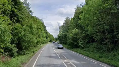 Generic image of the A500, a single carriageway main road, with tall trees on both sides.