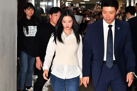 Getty Images New Jeans' Hanni walks alongside a man in a suit as she arrives to testify at the National Assembly for hearing on October 15, 2024 in Seoul, South Korea