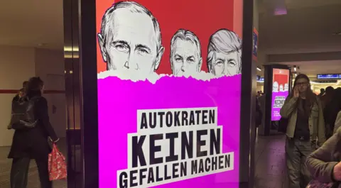 BBC/Imogen Foulkes A poster showing a slogan on a pink background along with the silhouettes of three men