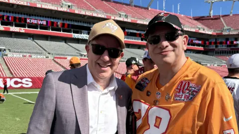 Kieron Hyam Kieron pictured with one of the Glazers - the family who own the Tampa Bay Buccaneers, on the pitch after the Denver Broncos game in September