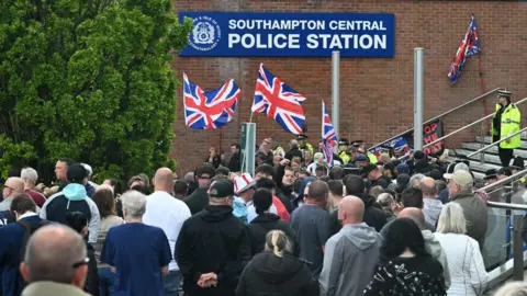 Getty Images A large crowd of protestors are pictured gathered outside Southampton Central Police Station. Some are waving Union Flags. 