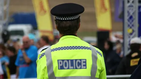 Getty Images The backmost  of a constabulary  serviceman  successful  a high-vis jacket, looking retired  implicit    a blurred crowd.