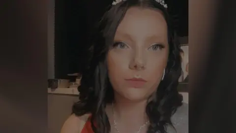 Billie Jeffreys Billie wearing a sleeveless sparkly top and a a tiara on her hair- taking a selfie