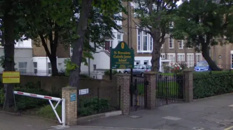 Google A Google street view showing the front of St Bernadette's school, showing the school gates, some trees and a pathway, as well as the school sign