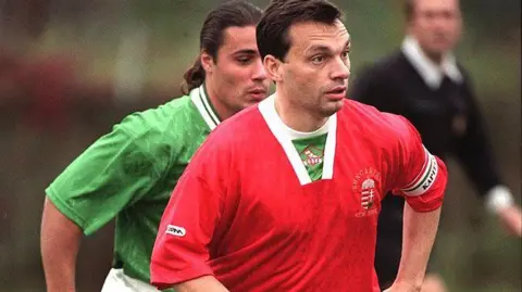 AFP via Getty Images A man plays football in a red shirt